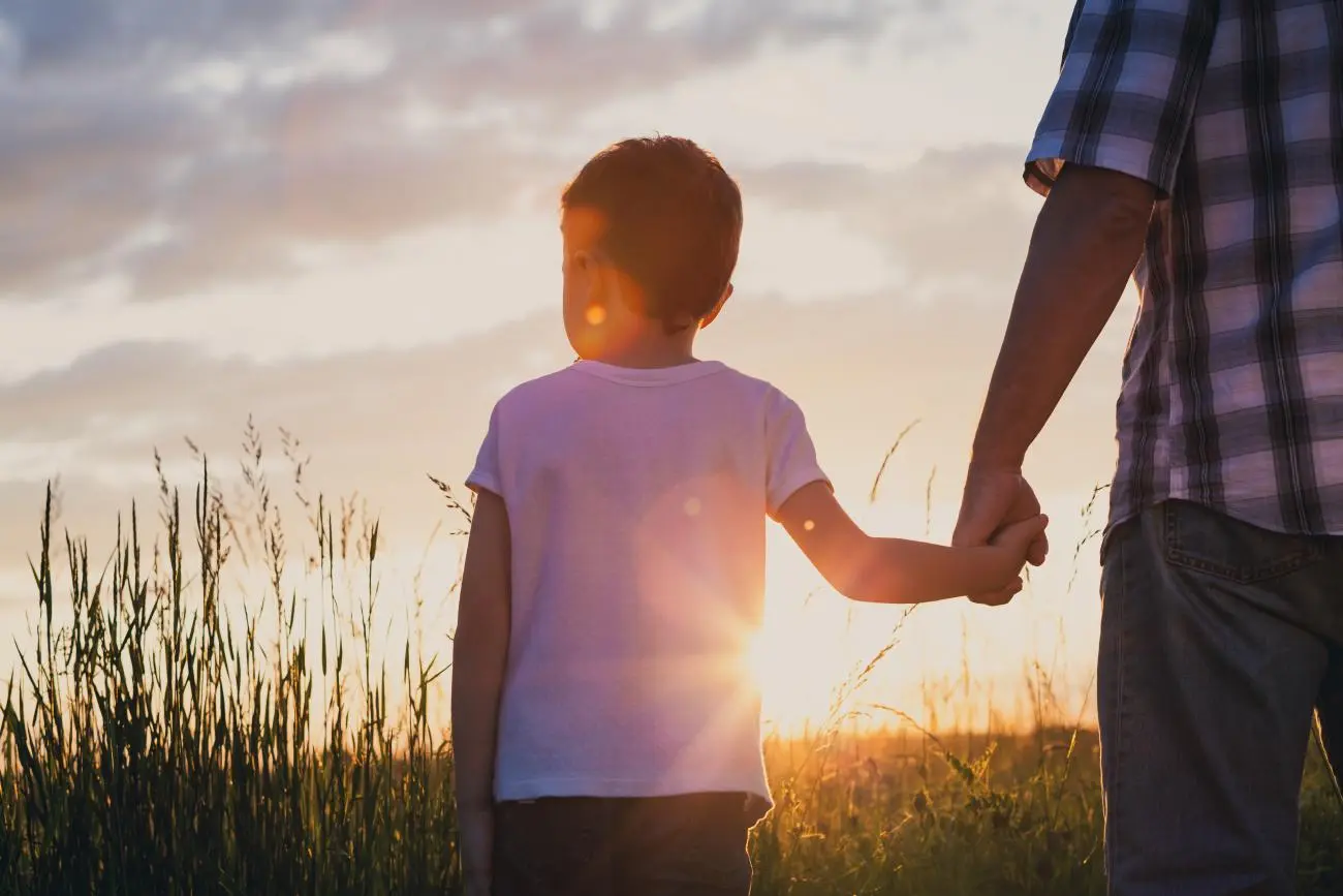 Kid holding parents hand watching the sunset. Life Insurance For Kids: Do You Really Need It?