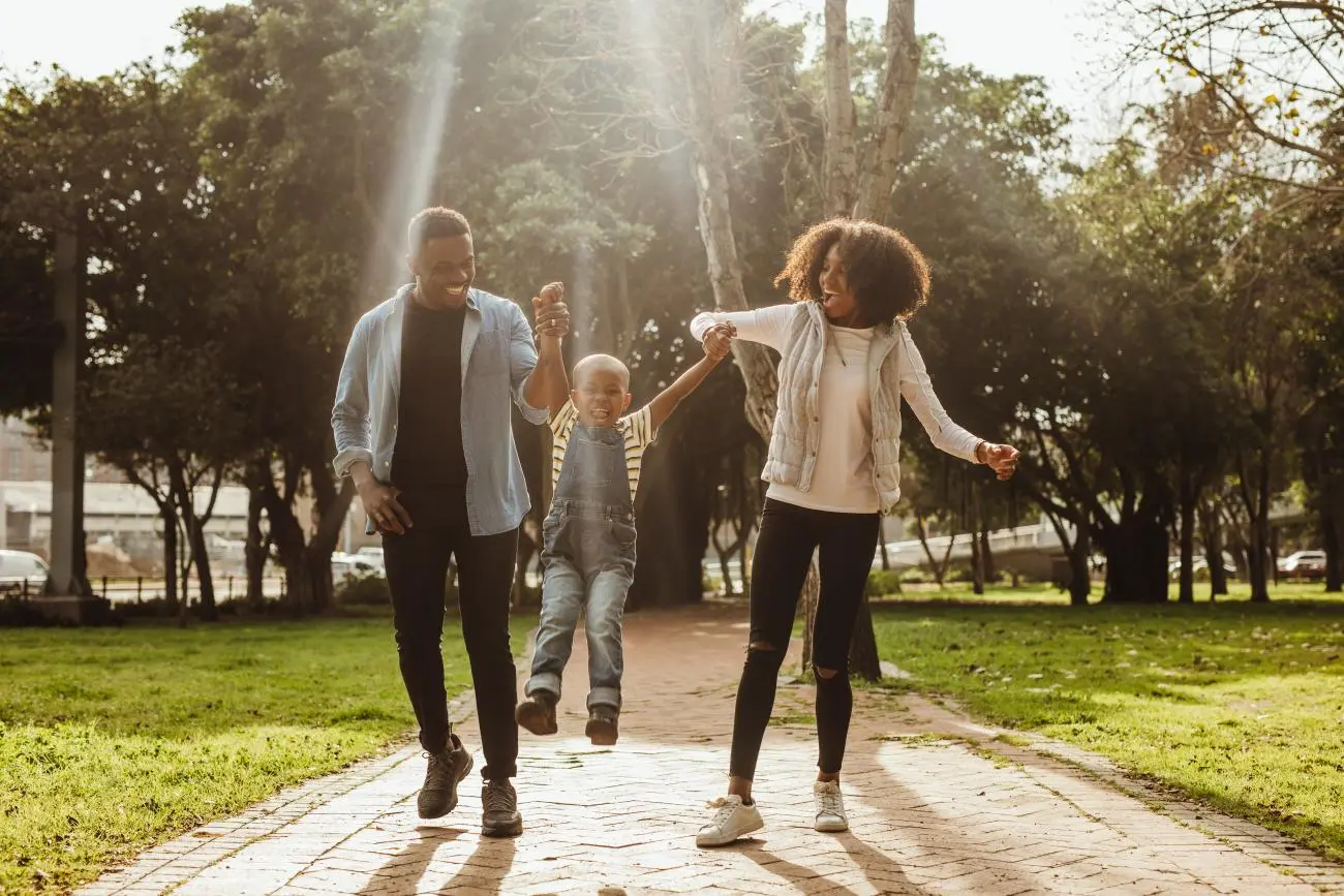 Five Reasons to Consider Life Insurance - family walking with their kid in a park smiling