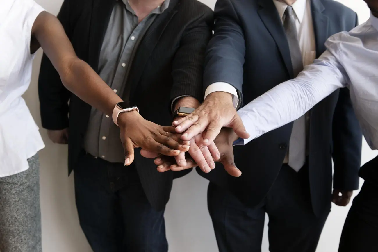 Diverse professionals collaborating with hands together, showcasing teamwork at Statera Financial Advisors.