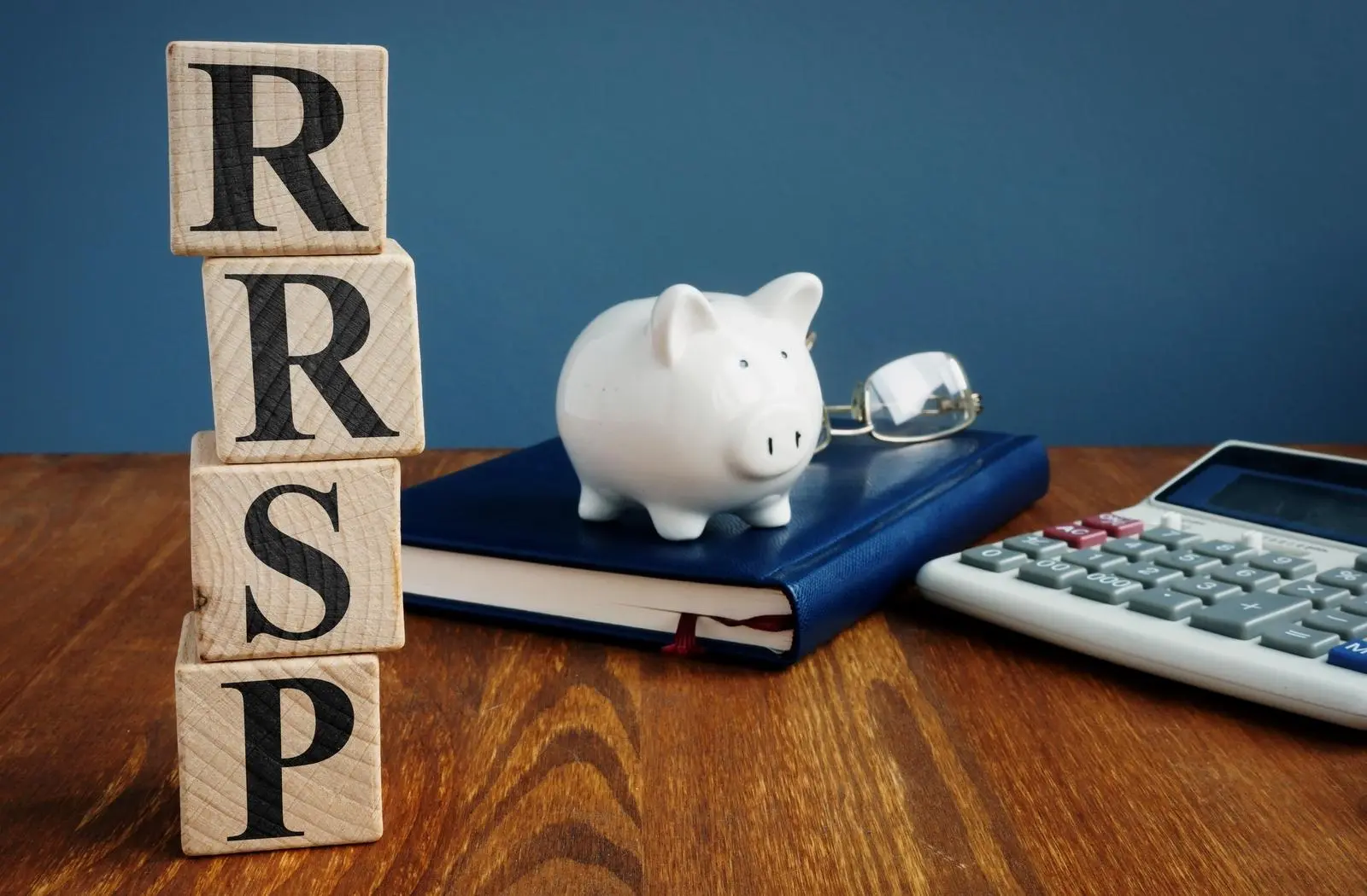 Wooden blocks spelling 'RRSP' with a piggy bank and calculator, symbolizing financial planning by Statera Planners.
