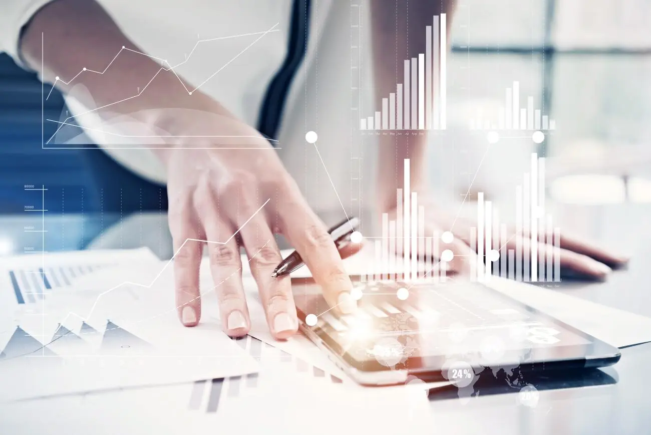 Human hand using a digital tablet with financial graphs, charts, and data visualization for Statera Financial Planners.